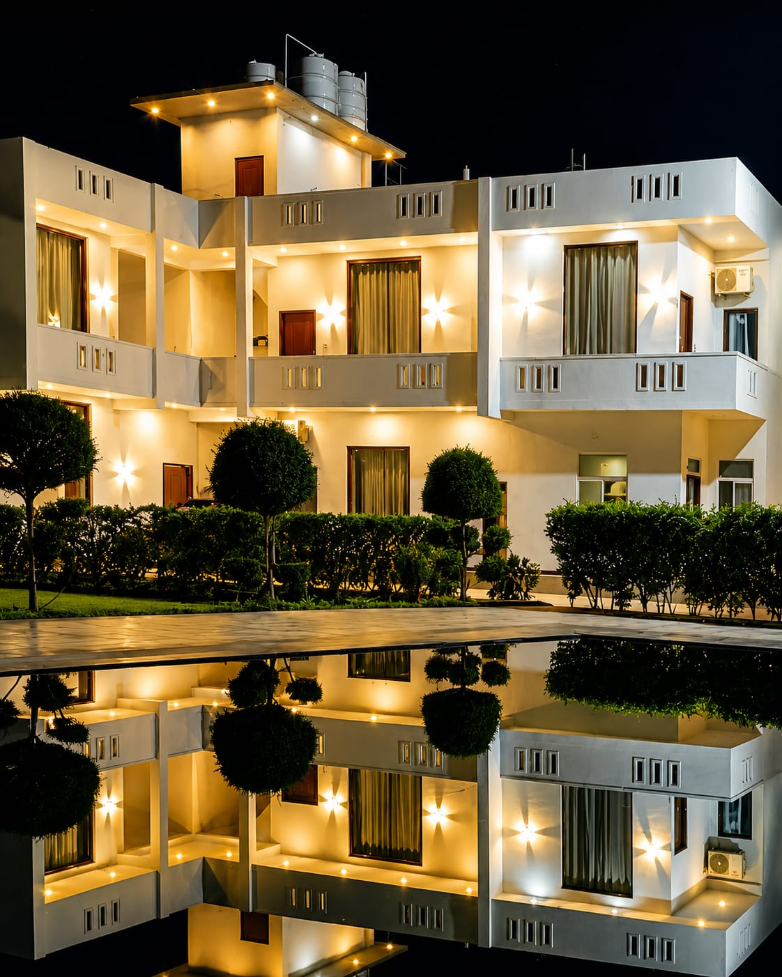 Mandiya Villa lit up at night with warm lights reflecting on the pool.