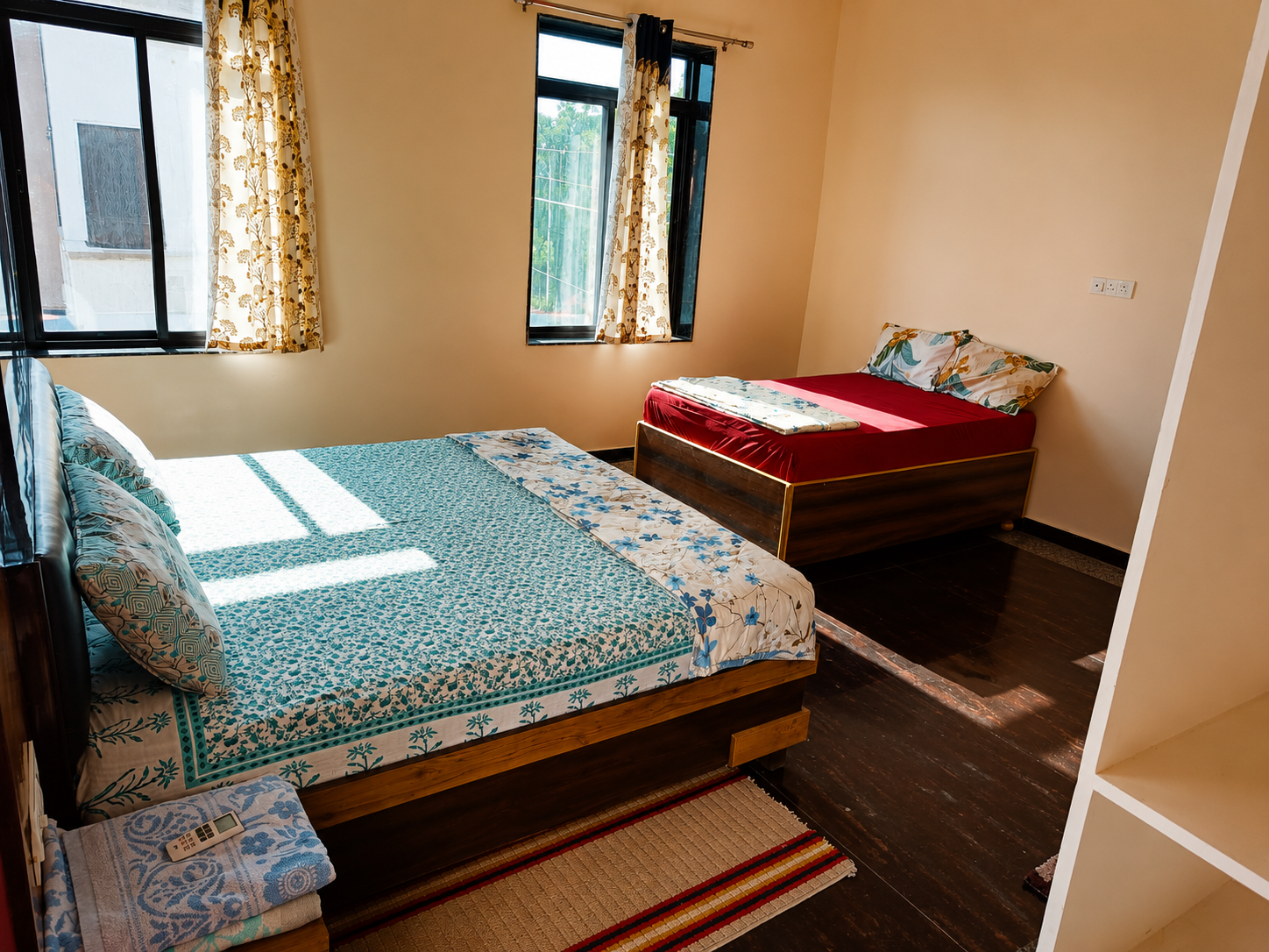 AC bedroom at Mandiya Villa with a double bed and a single bed, bright daylight through curtained windows.